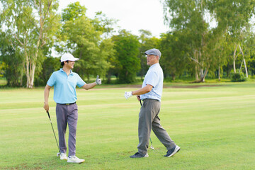 Asian man and elderly father are enjoy playing golf together with a good time.