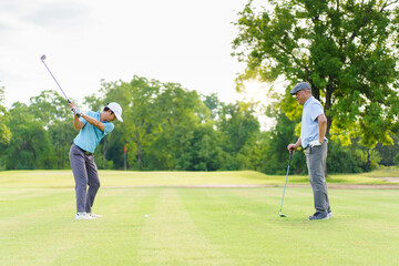 Asian man and elderly father are enjoy playing golf together with a good time.