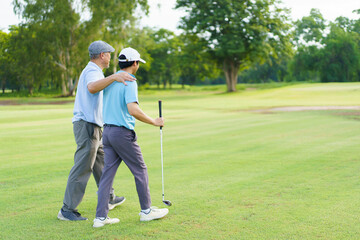 Asian man and elderly father are enjoy playing golf together with a good time.