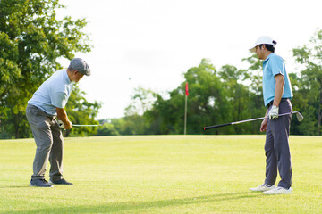 Asian man and elderly father are enjoy playing golf together with a good time.