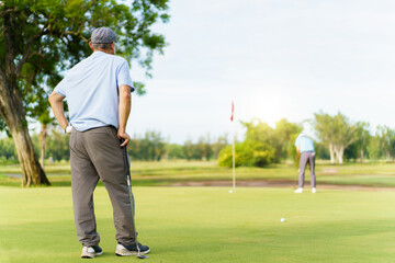 Asian man and elderly father are enjoy playing golf together with a good time.
