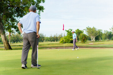 Asian man and elderly father are enjoy playing golf together with a good time.