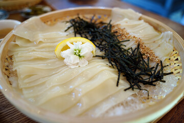 Glossy Cold Udon Noodles in a Bamboo Basket with Ice and Nori – Japanese Cuisine Close-Up