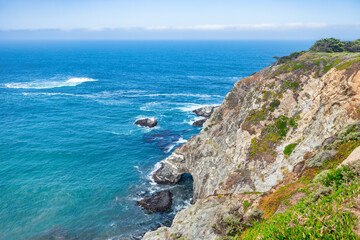 Iconic Bixby Creek Bridge stretches across the cliffs of Big Sur along Highway 1, with waves crashing below and lush hills meeting the Pacific Ocean on California's dramatic coast
