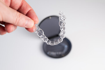 Doctor holding invisible aligner dental braces over case
