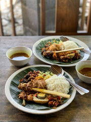 Nasi Campur is a Traditional Balinese rice dish served on a banana leaf with various side dishes, showcasing authentic Indonesian cuisine.