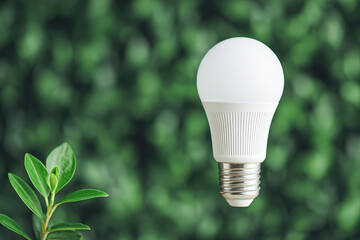 A modern LED light bulb floats beside a small green plant against a blurred natural background, symbolizing eco-friendly energy and sustainability.