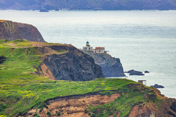 Scenic view of Point Bonita Lighthouse perched on a dramatic cliff along the Marin Headlands, overlooking the Pacific Ocean under soft coastal light