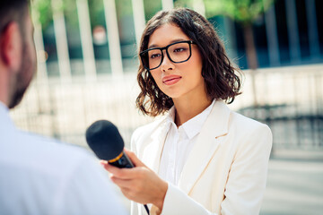 Professional young woman journalist conducting an outdoor interview with confidence and...