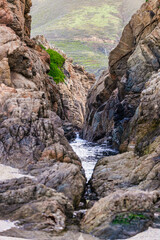 Scenic coastal view at Garrapata State Park near Big Sur, California, showcasing rugged cliffs, vibrant plants, and the Pacific Ocean along the iconic Highway 1 on a clear spring day