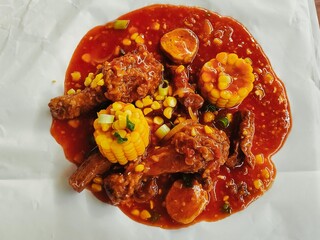 Close-up of crispy fried chicken topped with Asian sweet and spicy sauce. Added with sweet corn,...