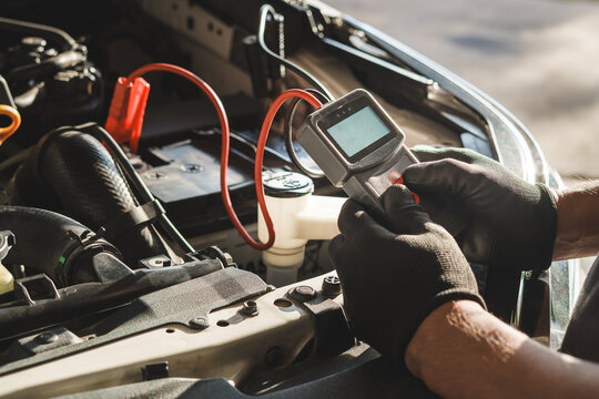 Car Mechanic Checking Battery with Diagnostic Tool