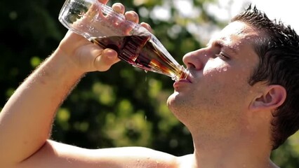 A man drinks a bottle of cold cola during a hot afternoon - Powered by Adobe