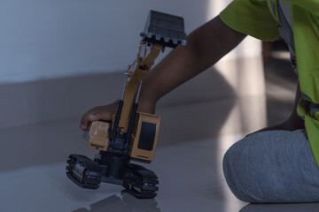 Child enjoys indoor play with a yellow toy excavator, great for illustrating indoor play, kids at leisure, and construction play.