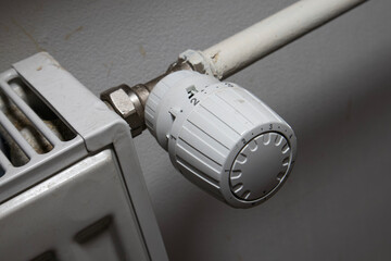 White thermostatic head on the battery. Heat regulation in the house. heating season