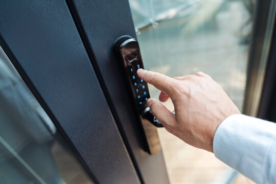Close-up of man's hand entering code on smart lock keypad. Concept of smart home security, access control and modern living.