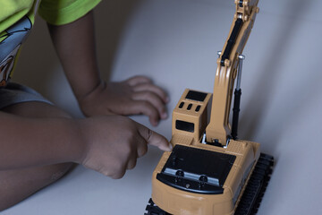 Child operates toy excavator using remote control, suitable for promoting educational toys for kids...