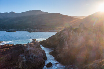 Sunset view of Garrapata State Park Bluff Trail along Highway 1, with rocky cliffs, deep blue...