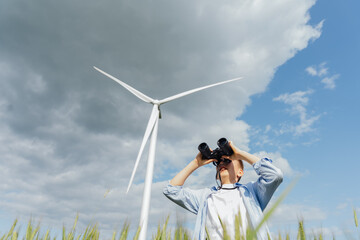 Teenage boy observing sky with binoculars near wind turbine
