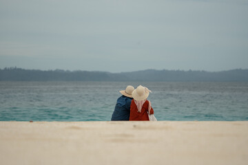 Two friends enjoy the beauty of Indonesia's tropical beaches. Two young women sit together and chat on a beautiful tropical beach