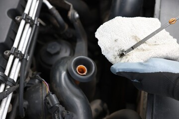 Worker checking motor oil level in car with dipstick, closeup