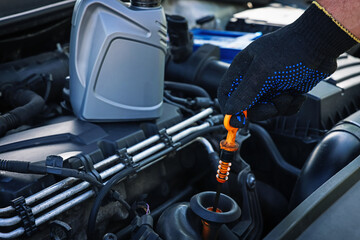 Worker checking motor oil level in car with dipstick, closeup
