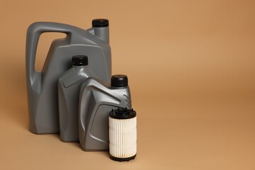Motor oil in plastic canisters and filter on beige background, space for text