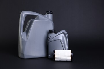 Motor oil in plastic canisters and filter on black background, space for text
