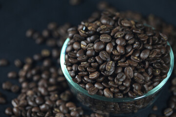 Aromatic Coffee Beans: An inviting composition of roasted coffee beans spills from a transparent bowl, showcasing their rich textures and inviting aroma. 
