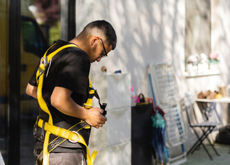 Construction worker adjusting safety harness before climbing