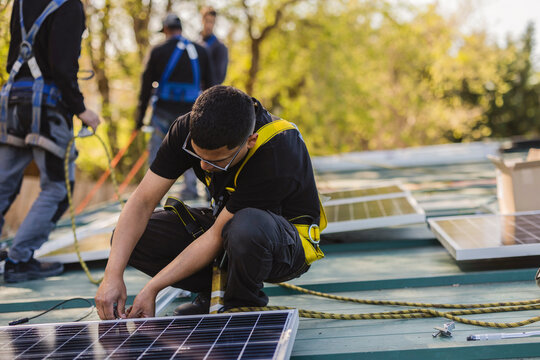 Workers installing solar panels on rooftop for green energy production