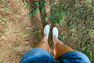 Top view of legs walking along a forest path in summer shorts.