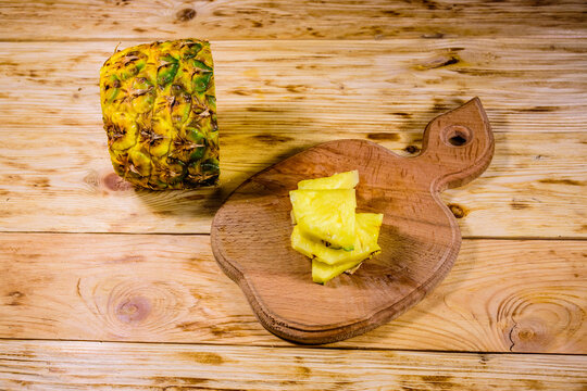 Cutting board with sliced pineapple on wooden table - Powered by Adobe