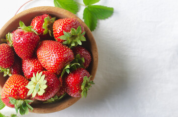 Ripe red strawberries in a ceramic bowl on a white background. Concept of summer berry harvest. Horizontal orientation. Selective focus. Top view. Copy space.