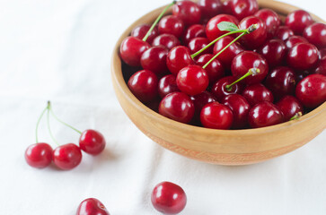Ripe red cherries in a ceramic bowl on a white background. Concept of summer berry harvest. Horizontal orientation. Selective focus.