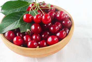 Ripe red cherries in a ceramic bowl on a white background. Concept of summer berry harvest. Horizontal orientation. Selective focus.