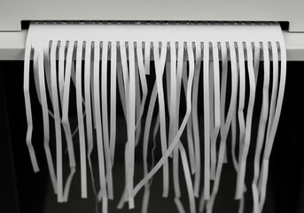 Secure Disposal: Shredding for Privacy - Paper shredder slicing white sheet into strips, symbolizing secure disposal, privacy, and data protection.
