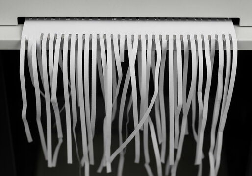 Secure Disposal: Shredding for Privacy - Paper shredder slicing white sheet into strips, symbolizing secure disposal, privacy, and data protection.