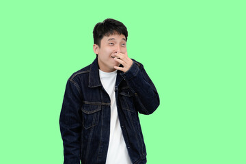 Young chinese Asian with Hand Covering Mouth, Looking funny and silly pose in green isolated...