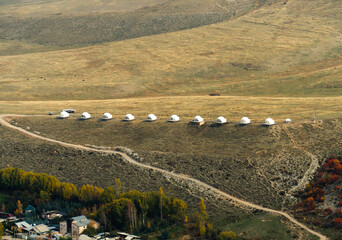 Modern yurt-like accommodation positioned in a row on a hillside near Karakol, Kyrgyzstan. 