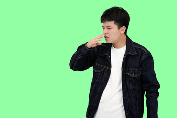 young asian man smell something bad in green isolated background