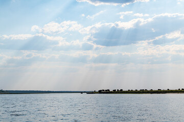 cloudscape with herd of elephants on the grassland at the riverside in Chobe National Park