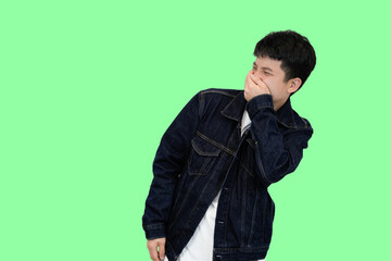 young asian man smell something bad in green isolated background