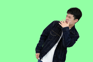 young asian man smell something bad in green isolated background