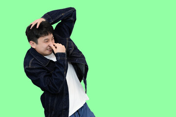young asian man smell something bad in green isolated background