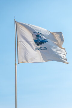 White flag with the logo of magdalena del mar municipality waving in the wind against a clear blue sky