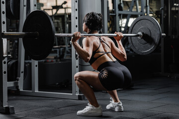 Strong athletic woman performing barbell squat at gym fitness workout glute muscle strength training