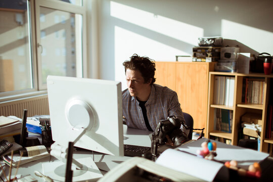 Male photographer reviewing camera in creative office workspace