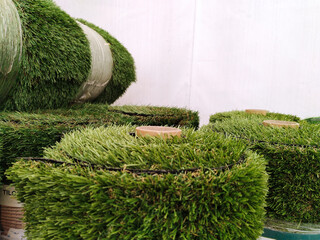 Rolls of green artificial grass in supermarket. Market for gardeners. Landscape design. Gardening....