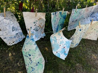 Close up marble pattern papers oil paint turps on water mix marbling design for original interior of book cover, fabric abstract blue green colour tones creation hanging pegs garden line to dry 